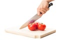 Hand holding a big knife, three tomatoes and wooden board Royalty Free Stock Photo