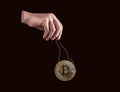 Hand holding bitcoin coin by strings. Manipulation in cryptocurrency exchanges, spoofing. Frauds with digital money Royalty Free Stock Photo