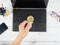 Hand hold bitcoin on the keyboard of laptop background on table top view workspace Royalty Free Stock Photo
