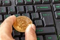 Hand holding bitcoin lying on computer keyboard Royalty Free Stock Photo
