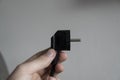 Hand holding black electric plug on a grey background. Royalty Free Stock Photo