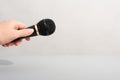 hand holding black microphone over grey background. copy space.media broadcast concept Royalty Free Stock Photo