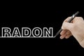 Hand holding a black pencil drawing a perfectly straight white line on black background with Radon text Royalty Free Stock Photo