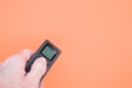Hand holding a black remote controller on an orange background Royalty Free Stock Photo