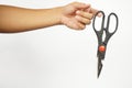 Hand holding a black scissor. Closed, not ready to cut position. White background