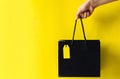 Hand holding black shopping bag with blank yellow price tag Royalty Free Stock Photo