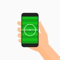 Hand holding smartphone with soccer field on the screen