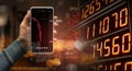 A hand holding a black smartphone showing stock market candlestick trend on blurred-out stock market data display panel, Business Royalty Free Stock Photo