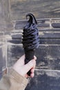 Hand holding black soft serve ice cream cone made with activated charcoal