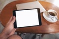 Hand holding black tablet pc with blank desktop white screen with laptop and coffee cup on wooden table Royalty Free Stock Photo