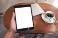 Hand holding black tablet pc with blank desktop white screen with laptop and coffee cup on wooden table Royalty Free Stock Photo