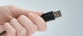 Hand holding black USB cable  on gray background Royalty Free Stock Photo