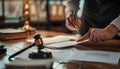hand holding black wooden gavel and bang on sounding block by blurred judge in library or courtroom background as concept of Royalty Free Stock Photo