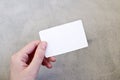 Hand holding a blank business card on gray background.