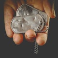 Hand holding blank and worn military dog tags with chain