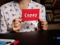 Hand holding a blank piece of paper with inscription Copay . Close up white business card