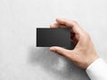 Hand holding blank plain black business card design mockup.