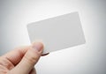 Hand holding a blank, rectangular white card against a neutral Royalty Free Stock Photo