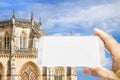 Hand holding a blank smartphone with a picture of Batalha cathedral in Portugal (Europe) - 3D render with copy space