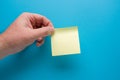 Hand holding blank yellow post-it on blue background Royalty Free Stock Photo