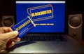 Hand holding Blockbuster membership card on laptop computer