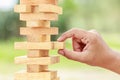 Hand holding blocks wood game (jenga) on blurred green background. Risk concept Royalty Free Stock Photo