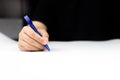 Hand holding blue ball-pen writing on white paper Royalty Free Stock Photo