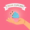 Hand holding blue cream cupcake