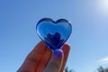 hand holding a blue glass heart against a clear sky Royalty Free Stock Photo