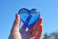 hand holding a blue glass heart against a clear sky Royalty Free Stock Photo