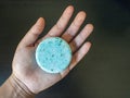 Hand holding a Blue Shampoo bar before use in the shower version 1