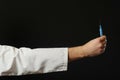 Hand holding blue syringe with blue vaccine on dark background. Health care concept. Offer of vaccination Royalty Free Stock Photo