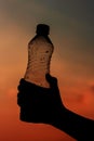 Hand holding bottle water on sunset sky,Summer holiday vacation outdoor and view in evening, Royalty Free Stock Photo