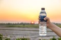 Hand holding bottle water on sunset sky,Summer holiday vacation outdoor and view in evening,Drinks, people and lifestyle Royalty Free Stock Photo