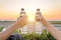 Hand holding bottle water on sunset sky,Summer holiday vacation outdoor and view in evening,Drinks, people and lifestyle Royalty Free Stock Photo