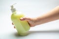 Hand holding bottle with yellow antiseptic liquid soap at an angle on a white background. Horizontal orientation Royalty Free Stock Photo