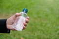 Hand holding a bottled water on green grass blur background Royalty Free Stock Photo