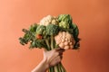 Hand holding a bouquet of vegetables on a pastel colored background, created with Generative AI technology