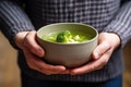 hand holding bowl of beef and broccoli soup