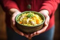 hand holding bowl of chicken and rice soup