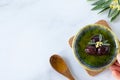 Hand holding bowl with natural extra virgin olive oil and black olives, green tree branch and wooden spoon on white, top view Royalty Free Stock Photo