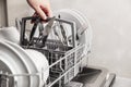 Hand holding box with clean cutlery in open dishwasher in the home kitchen Royalty Free Stock Photo