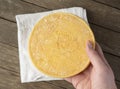 Hand holding brazilian Canastra artisanal cheese over wooden background