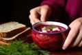 hand holding bread slice on side of borscht bowl