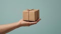 Hand holding brown box on light blue background, simple delivery mockup for packaging gift parcel concept. Royalty Free Stock Photo