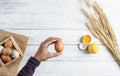 Hand holding brown egg on white wood background Royalty Free Stock Photo