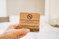 hand holding brown grunge paper with non smoking room on blurred bedroom background