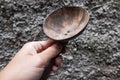 The hand holding a brown wooden rice ladle, with a wall in the background