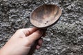 The hand holding a brown wooden rice ladle, with a wall in the background Royalty Free Stock Photo