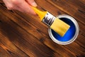 Hand holding a brush over can of paint on a wooden table - Image Royalty Free Stock Photo